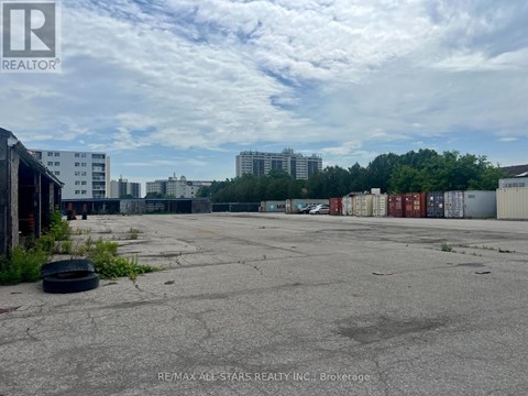 A large, empty parking lot with a few buildings in the background.