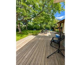 A wooden deck with a black folding chair and a blue cooler box.
