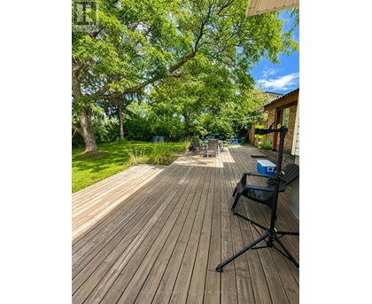 A wooden deck with a black folding chair and a blue cooler box.