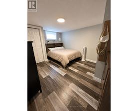 A bedroom with a bed, nightstand, and a coat rack.