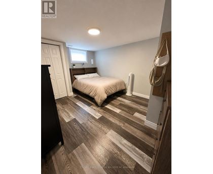 A bedroom with a bed, nightstand, and a coat rack.
