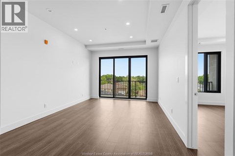 A spacious room with a sliding glass door leading to a balcony.