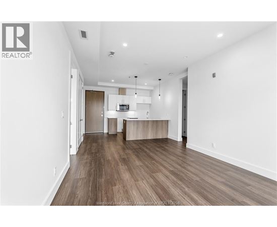 A spacious living room with wood flooring and white walls.
