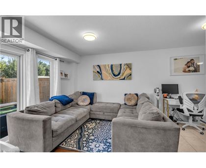 A living room with a grey couch and a painting on the wall.