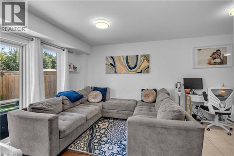 A living room with a grey couch and a painting on the wall.