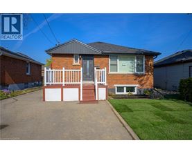 A red brick house with a white fence in front.