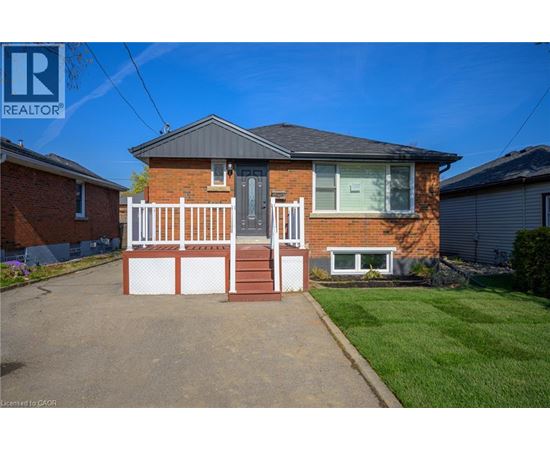 A red brick house with a white fence in front.