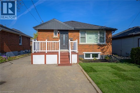 A red brick house with a white fence in front.