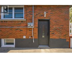 A red brick house with a grey door and a window.