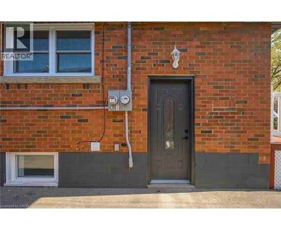 A red brick house with a grey door and a window.