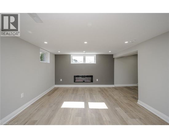 A spacious room with a fireplace and wood flooring.