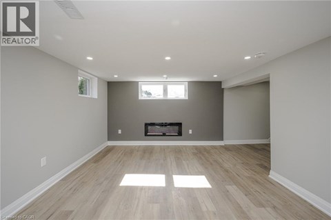 A spacious room with a fireplace and wood flooring.