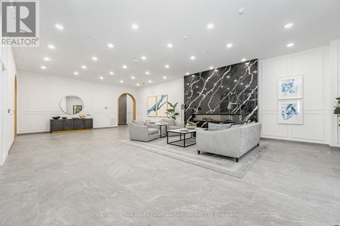 A spacious living room with a grey sofa and a marble wall.