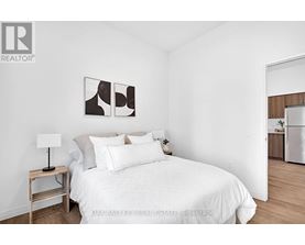 A bedroom with a white bed and a lamp on a side table.