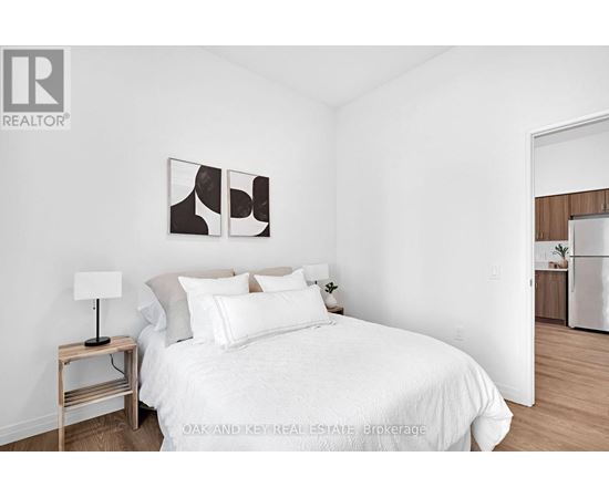 A bedroom with a white bed and a lamp on a side table.