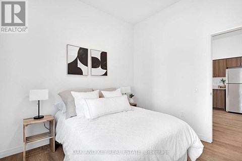 A bedroom with a white bed and a lamp on a side table.