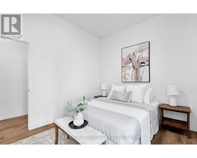 A bedroom with a white bed and a framed picture on the wall.