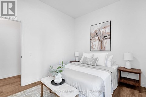 A bedroom with a white bed and a framed picture on the wall.