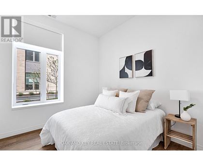 A bedroom with a white bed and a painting on the wall.