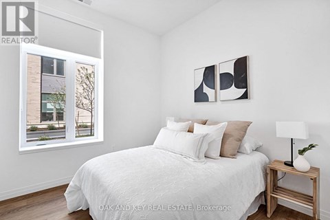 A bedroom with a white bed and a painting on the wall.