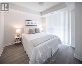 A bedroom with a bed, nightstand, and a picture frame on the wall.