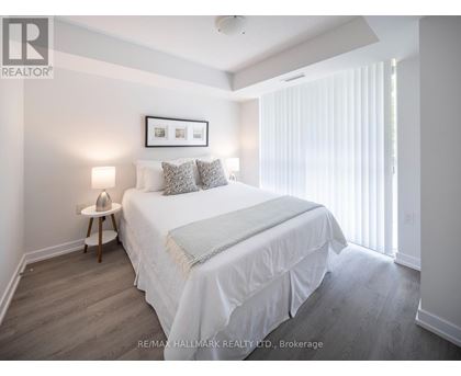 A bedroom with a bed, nightstand, and a picture frame on the wall.