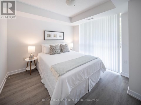 A bedroom with a bed, nightstand, and a picture frame on the wall.