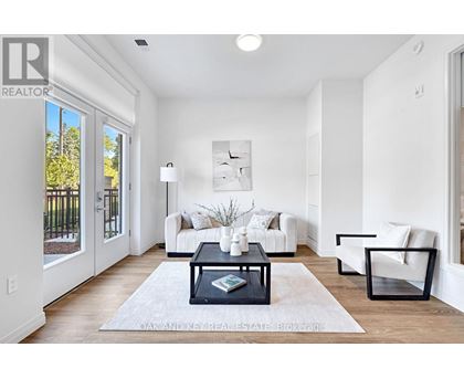 A well-lit, modern living room with a white sofa set, a coffee table, and a large window.