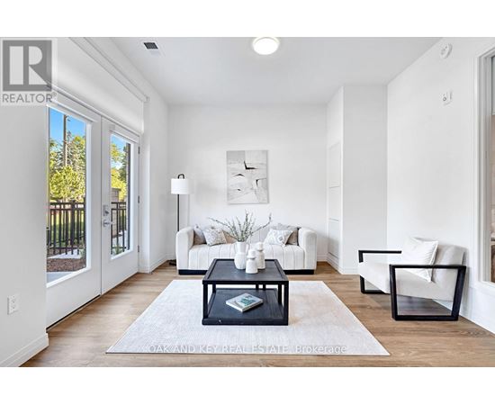 A well-lit, modern living room with a white sofa set, a coffee table, and a large window.