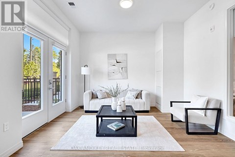 A well-lit, modern living room with a white sofa set, a coffee table, and a large window.