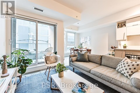 A living room with a couch, chair, and potted plants.