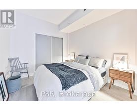 A bedroom with a bed, chair, and nightstand.