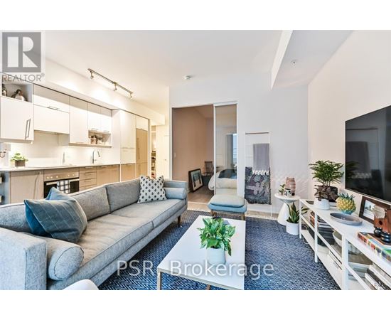 A living room with a grey sofa and a television on the right side.
