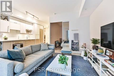 A living room with a grey sofa and a television on the right side.