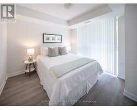 A bedroom with a bed, nightstand, and a picture frame on the wall.