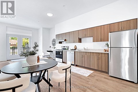 A modern kitchen with a glass table and chairs, a refrigerator, and wooden cabinets.