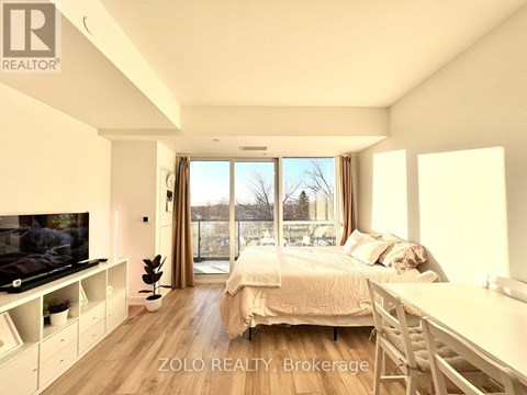 A bedroom with a large bed, a television, and a sliding glass door.