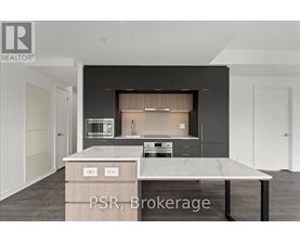 A modern kitchen with a marble countertop and dark cabinets.