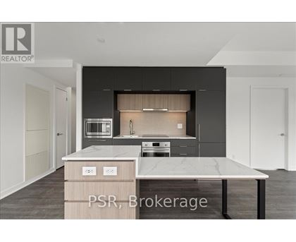 A modern kitchen with a marble countertop and dark cabinets.