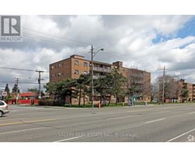A street view of a residential area with apartment buildings and a car parked on the side of the road.