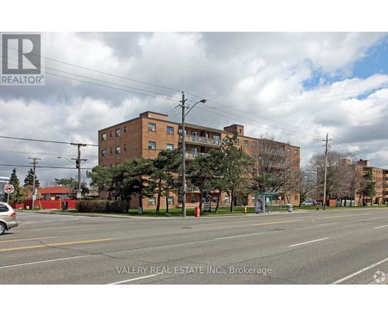 A street view of a residential area with apartment buildings and a car parked on the side of the road.