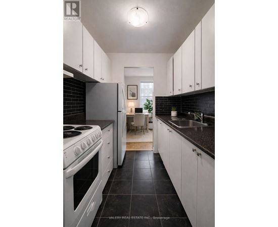 A modern kitchen with white cabinets and black countertops.