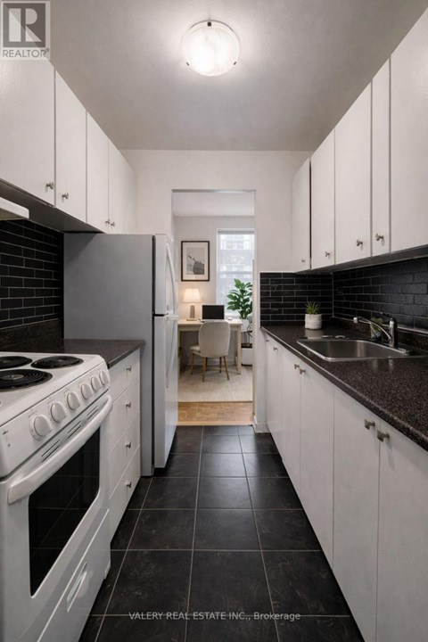 A modern kitchen with white cabinets and black countertops.