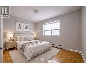 A bedroom with a bed, nightstands, and pictures on the wall.