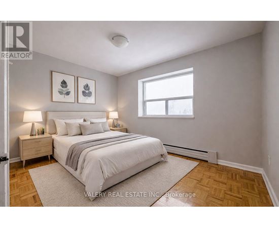 A bedroom with a bed, nightstands, and pictures on the wall.