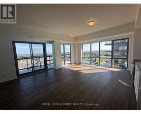 A spacious room with wooden floors and large windows overlooking a cityscape.
