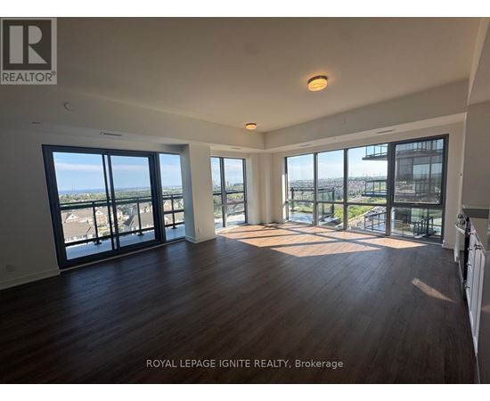 A spacious room with wooden floors and large windows overlooking a cityscape.
