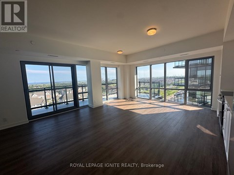 A spacious room with wooden floors and large windows overlooking a cityscape.