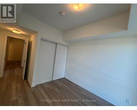A room with white walls and wooden flooring, with a door on the left and a closet on the right.