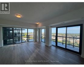 A spacious room with wooden floors and large windows overlooking a cityscape.